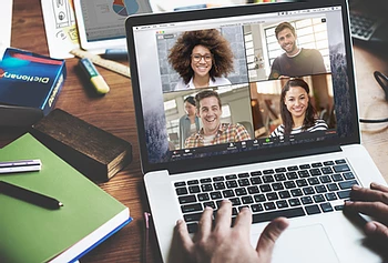 A computer running an online meeting with a diverse group of people.