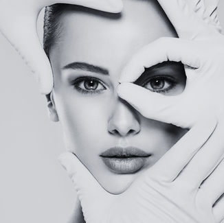 Face framed by gloved hands in a black-and-white image, conveying an introspective mood. Hands accentuate the face.