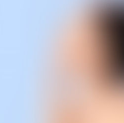 Profile of a woman touching her chin, facing left against a light blue background. She appears calm and serene with neutral lighting.