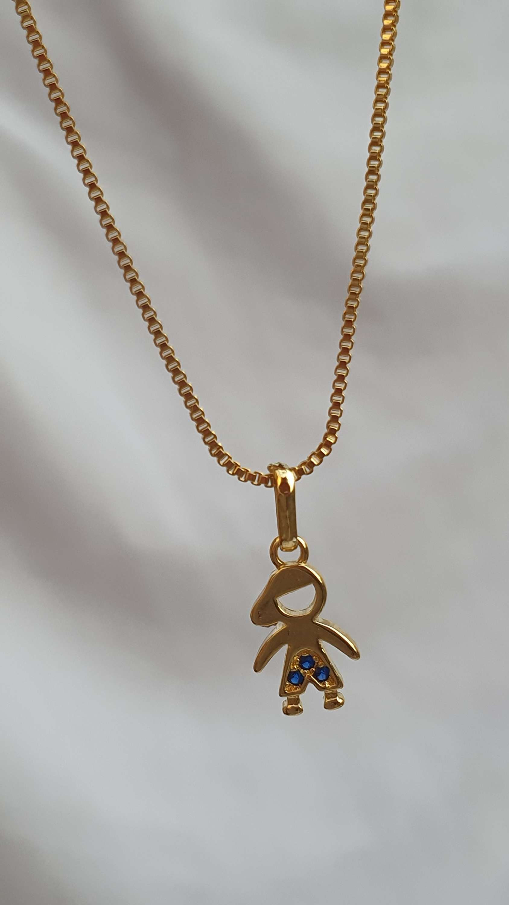 colar feminino corrente veneziana com pingente fihos, menino com bermuda cravejada de zirconias azul, banhada a ouro.