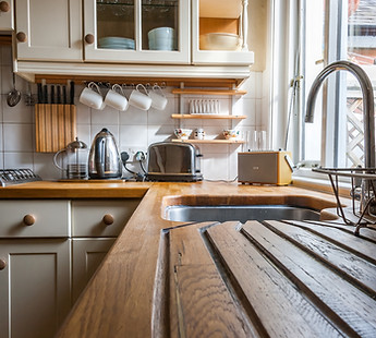 A view of a wooden draining board with kitchen applinaces in the background
