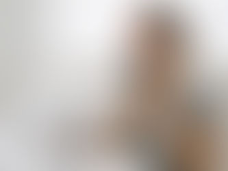 Mujer en reposo en la cama, con una compresa fría en la mejilla y la mano en el pecho, en un dormitorio blanco.
