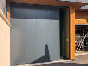 Porte de garage à cinq vantaux en panneaux d’épicéa peint gris anthracite, posé sur rails métalliques, haut et bas