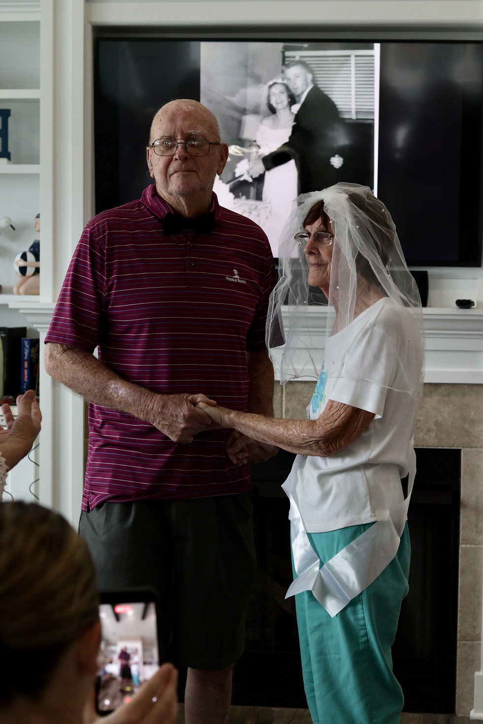 A couple holding hands during a vow renewal, she in a veil