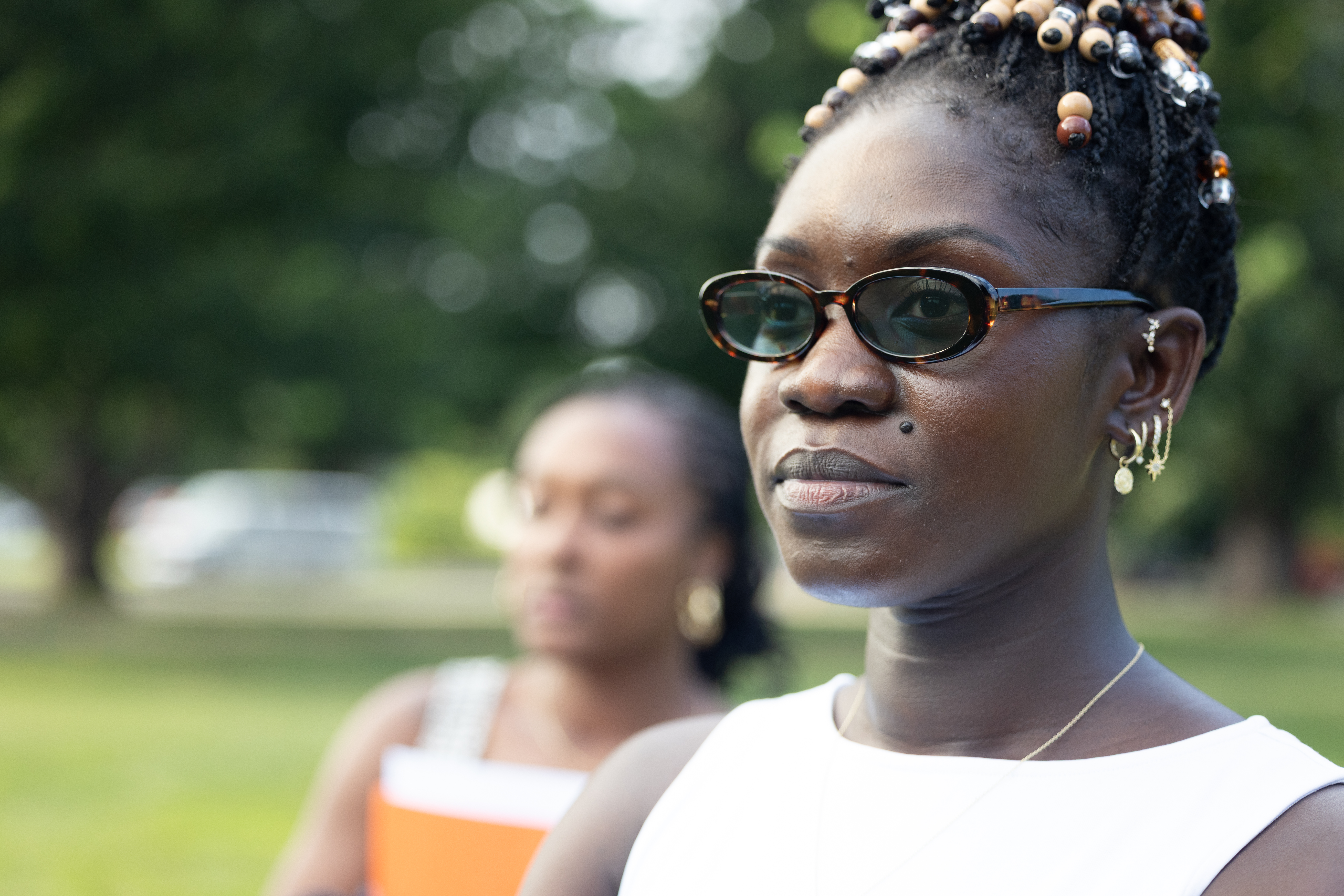 Portrait of a woman in sunglasses and a white top, outdoors on a lawn