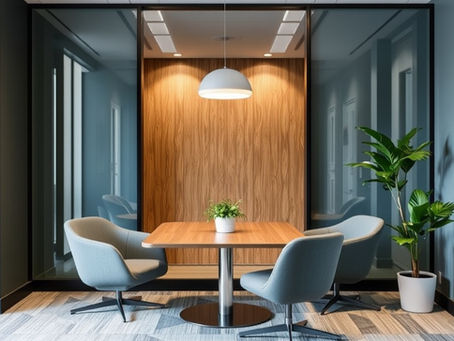 A modern office meeting area with a sleek wooden table, stylish gray chairs, vibrant greenery, and a contemporary pendant light.
