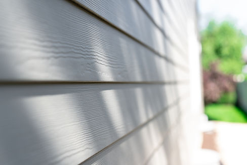 Close-up of a wooden house siding showing texture and details, with shadows and sunlight c