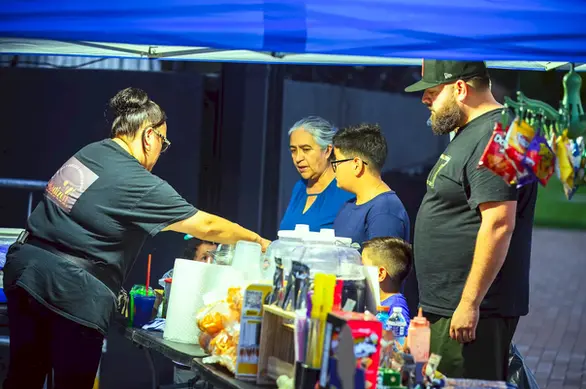 Vendedor atendiendo un puesto de comida y bebidas durante el evento comunitario