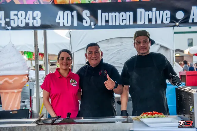 Vendedores de comida posando en su puesto durante HispanoFest 2026 en Melrose Park