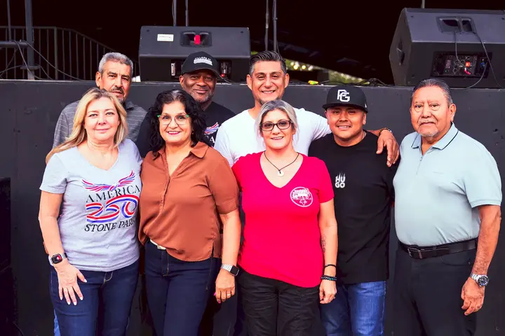 Representantes de la comunidad posando juntos cerca del escenario de Music in the Park 2026