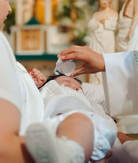 Professional baptism photography in Chicago capturing a baby baptism ceremony with family and priest during a Latino church celebration.