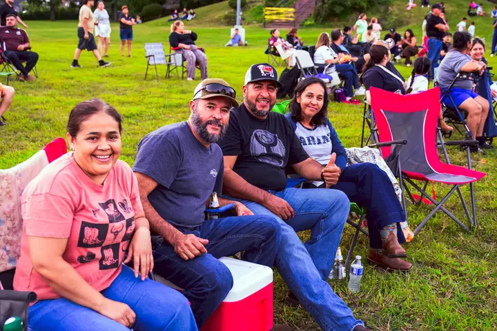 Grupo de asistentes sentado en el césped durante el evento de música en vivo