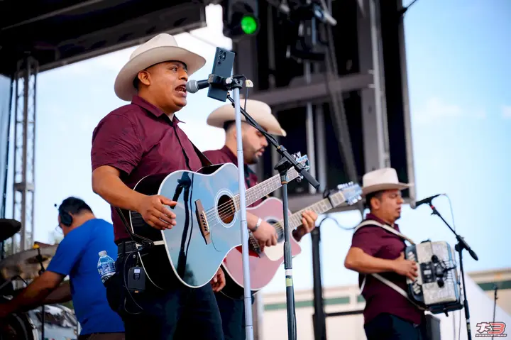 Guitarrista con sombrero blanco actuando en el escenario de HispanoFest 2026