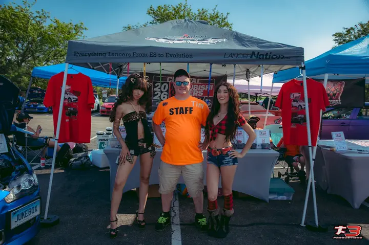 Tiny of the Cosplay Alliance Elite Team posing with event staff at the merchandise booth