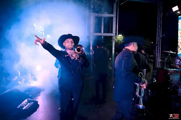 Cantante con sombrero negro actuando entre luces y humo en HispanoFest 202