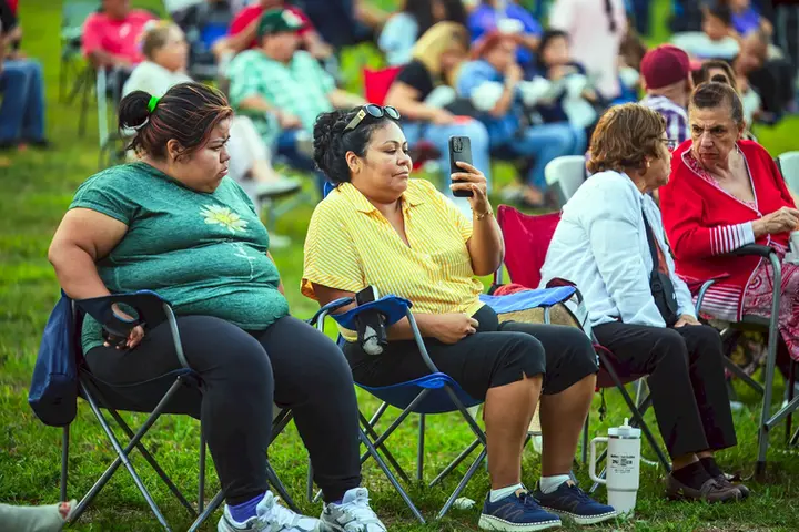 Residentes de Stone Park disfrutando del concierto comunitario en sillas de jardín