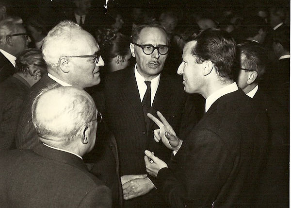 his image is a photograph of the Journalist to the king, Kurt Gruenebaum and King Baudouin taken in 1969. Kurt Grunebaum is pictured on the far left speaking to King Baudouin on the far right.