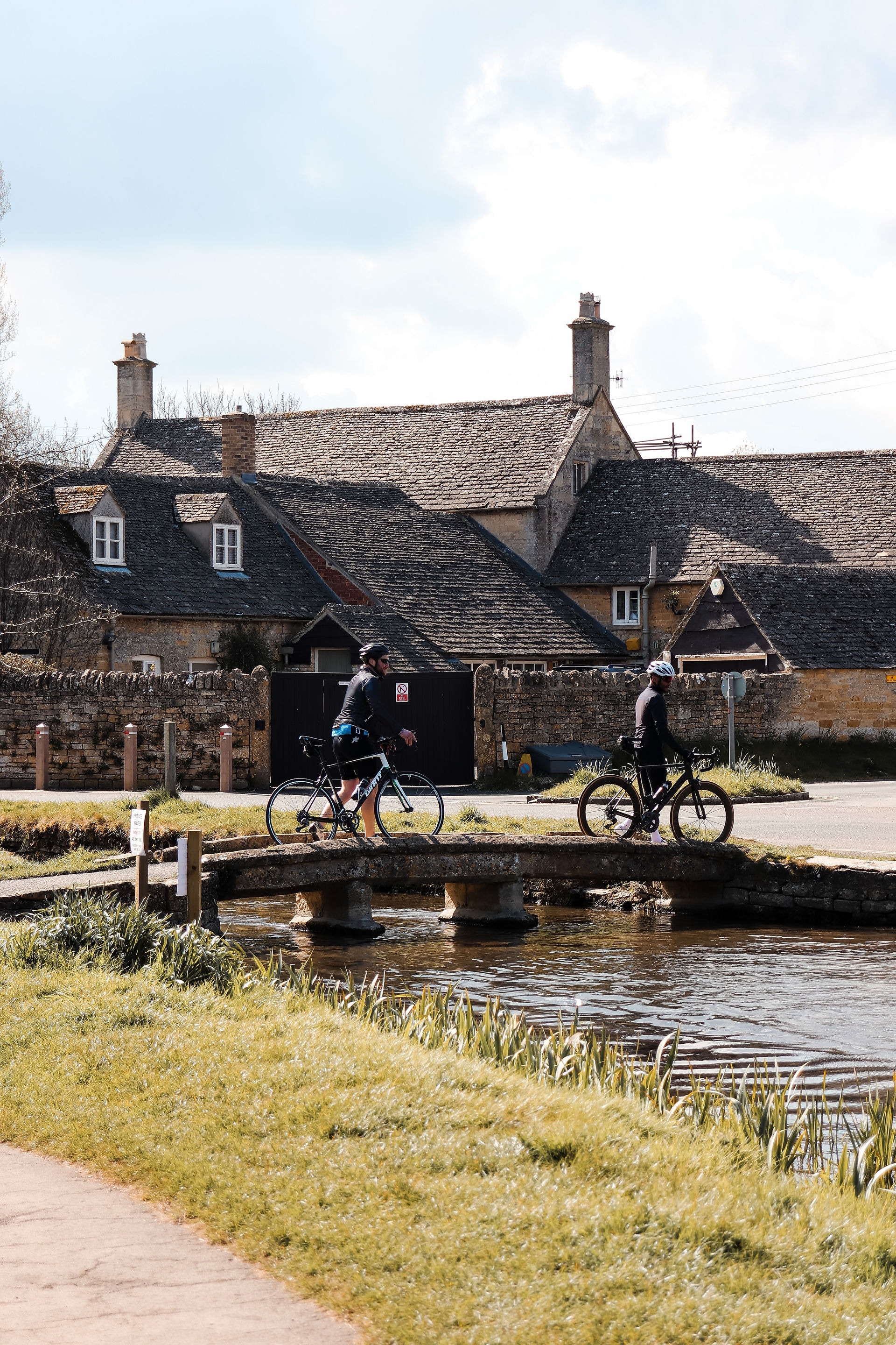 Cyclists in the Cotswolds - traditional village crossing