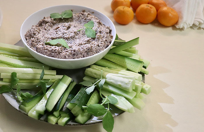 a bowl of lentil walnut pate served on a bed of raw veg for dipping