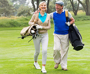 couple walking across golf course enjoying the game smiling
