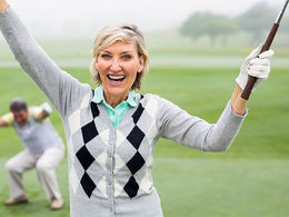 woman golfing holding up her club celebrating a shot