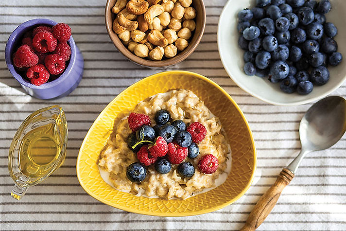 a bowl of oatmeal surrounded by bowls of berries and nuts