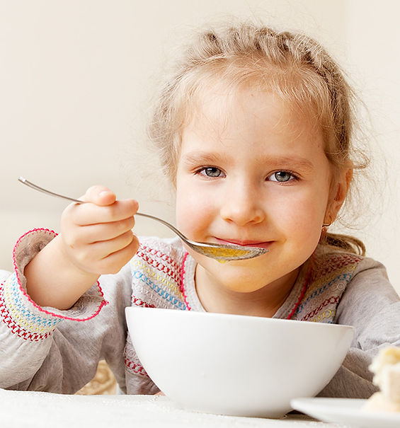 little white child eating from a soup bowl with a spoon