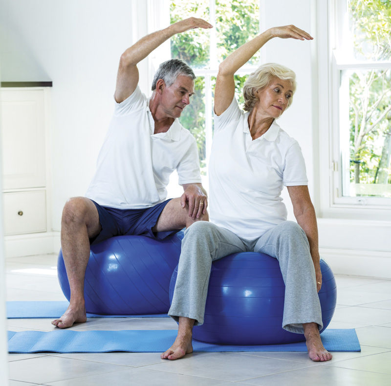 Older couple stretch on exercise balls