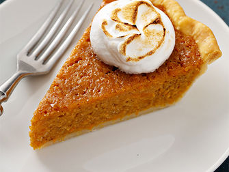 slice of sweet potato pie on a white plate and topped with whipped cream