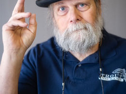 Picture of Dave Trout wearing a bowler and waving to the camera selling insurance