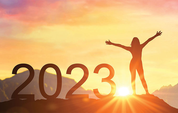 gratuitous imagea of a person on a mountain looking into the sun with "2023" next to them