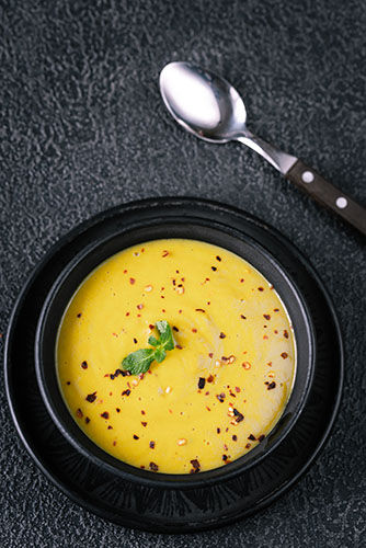 turmeric and coconut soup in a black bowl