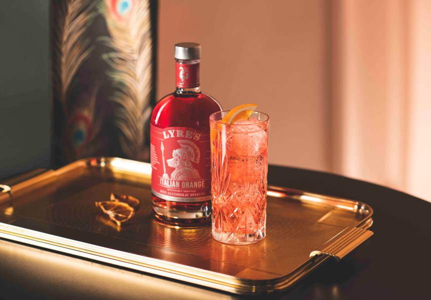 Lyres red bottle with orange cocktail in tall glass