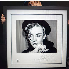 Black and white framed photo of Boy George in a black hat with his autograph underneath