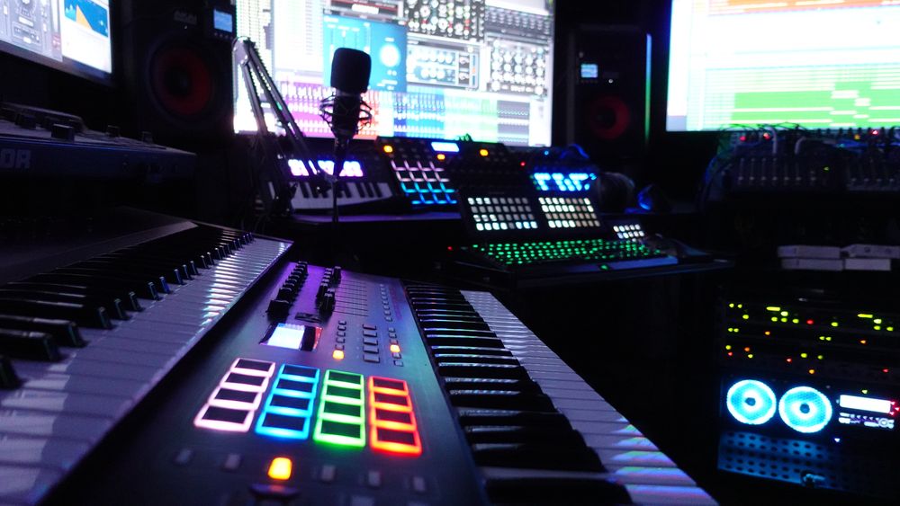 Musikproduktionsplatz im Edgar Studio mit Keyboards, Mikrofon und beleuchteten Controllern