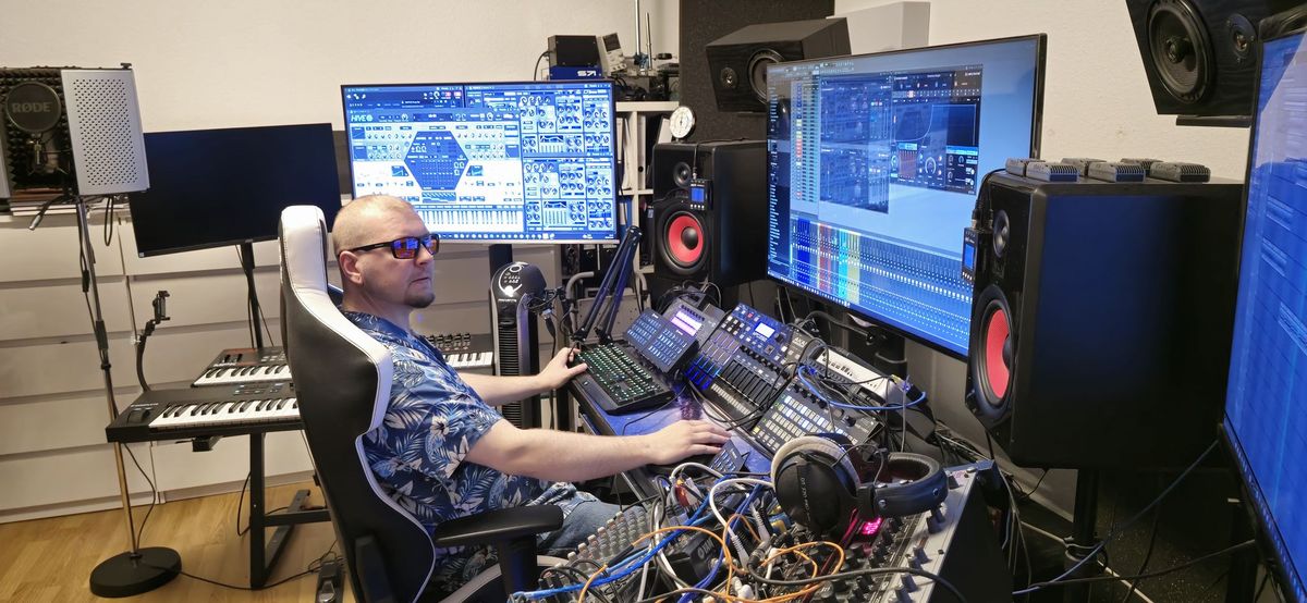 Mixing-Arbeitsplatz mit Produzent, Keyboards, Mischpult und großer DAW-Ansicht