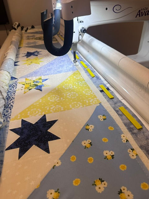 Eye-level view of a yellow and blue quilt loaded on a longarm quilting frame.