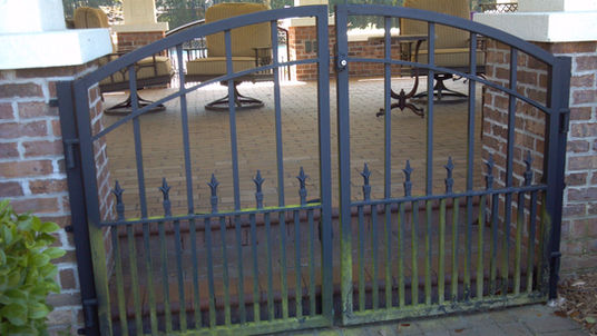 Metal gate with patio furniture in background.