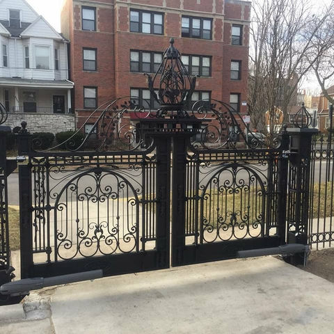 a wrought iron gate with a brick building in the background