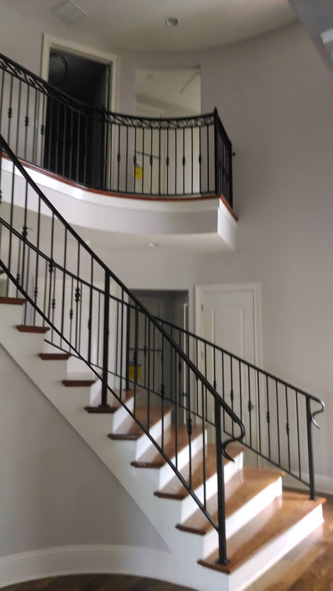 Curved staircase with black railing in modern interior.