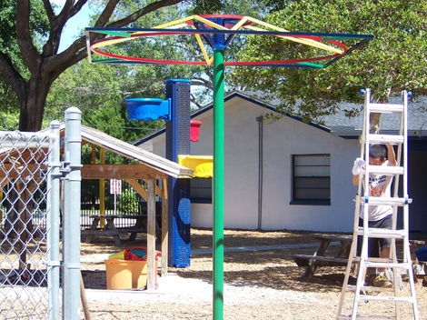 Colorful playground equipment with trees and building background.