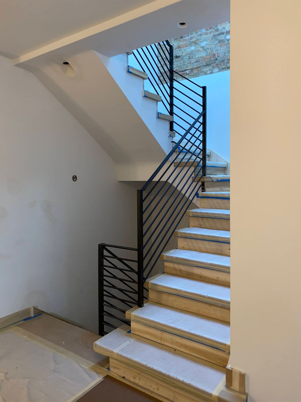 Modern staircase with black metal railing.