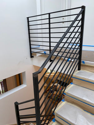 a staircase with blue tape on the steps and a black railing