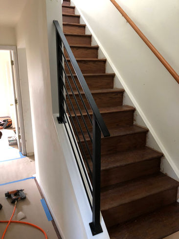 Wooden staircase with black metal railing.
