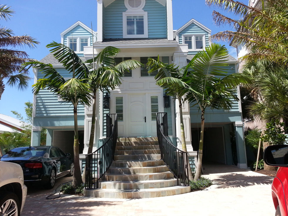 Blue house with palm trees and stairs in front.