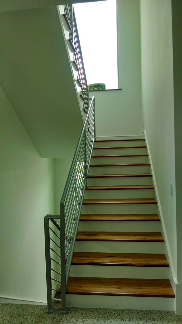 Narrow staircase with metal railing and wooden steps.