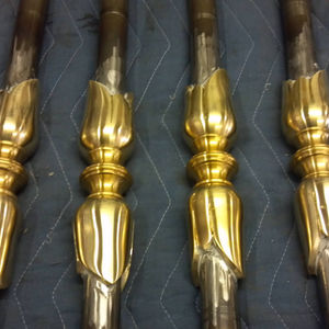 Four ornate, gold-colored metal rods aligned vertically.