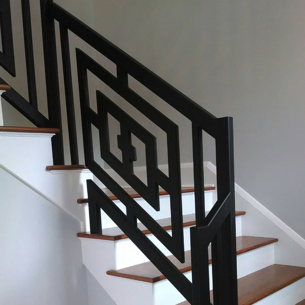 Black geometric railing on a wooden staircase.