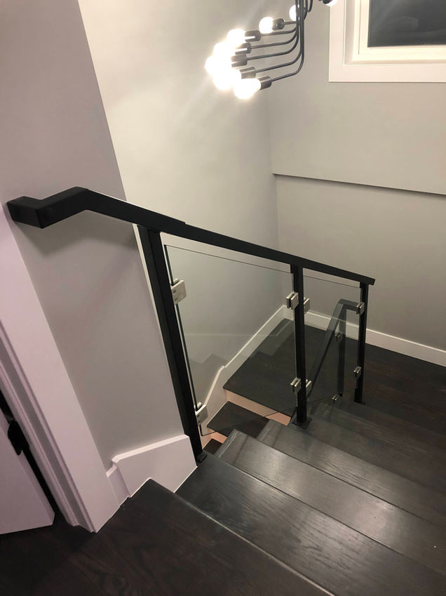Modern staircase with glass and metal railing.
