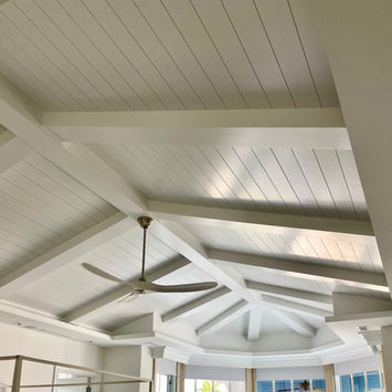 White vaulted ceiling with exposed beams and fan